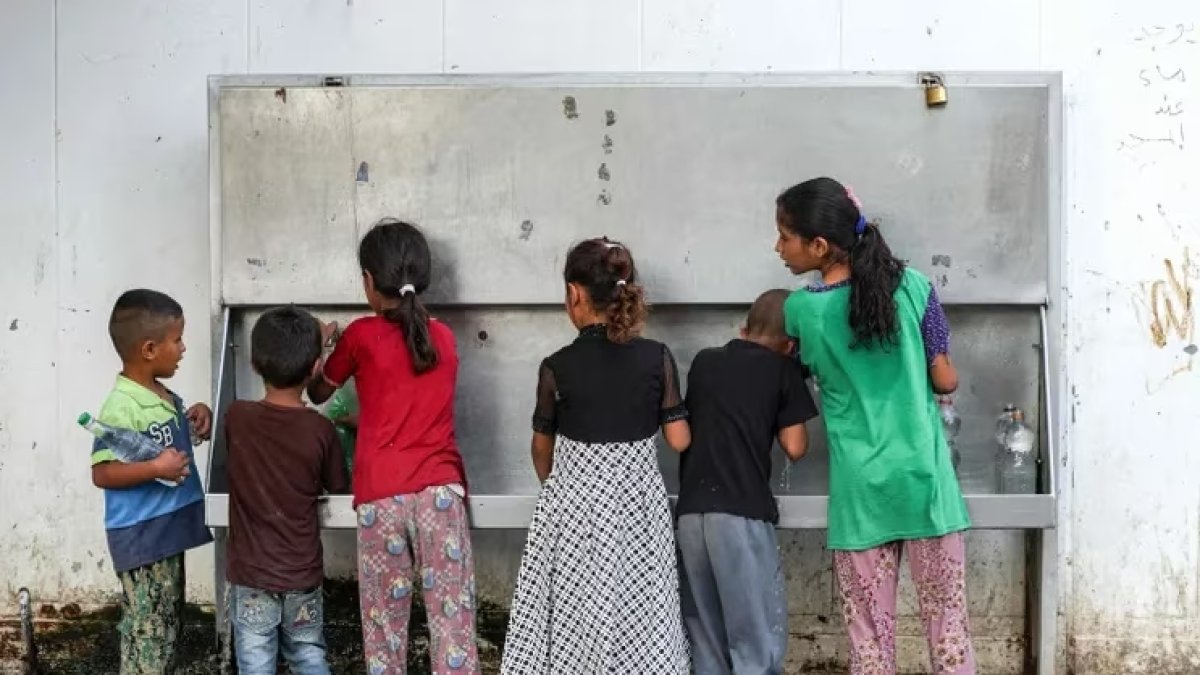 Niños llenan botellas con agua en una aldea en la franja de Gaza el pasado 28 de agosto