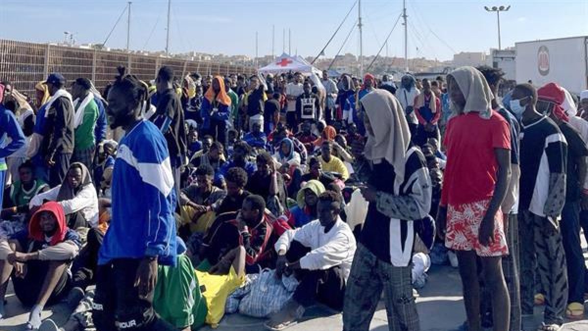 Un grupo de migrantes espera en la isla de Lampedusa mientras las autoridades italianas se preparan para trasladar a las personas tras los recién llegados, Italia, 13 de septiembre de 2023