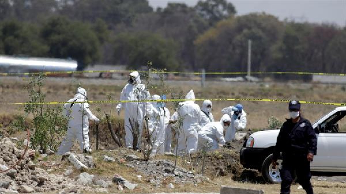 Fotografía de archivo de peritos forenses que realizan el levantamiento de cuerpos hallado