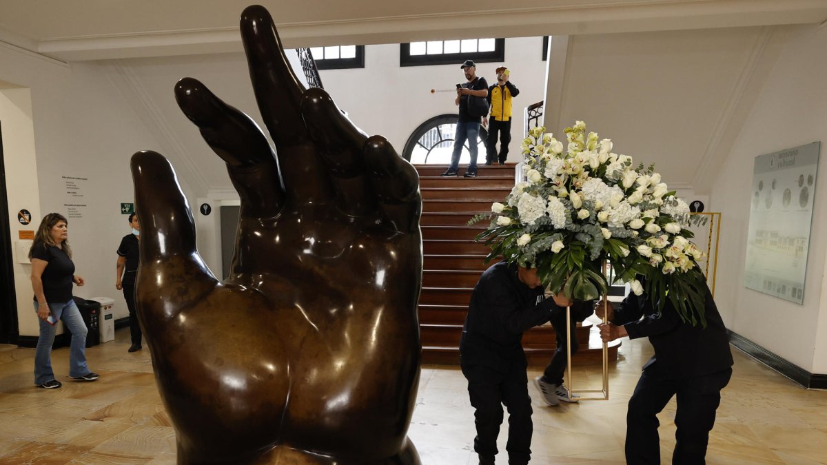 Empleados dejan un arreglo floral junto a la escultura La Mano de Fernando Botero, en el Museo Fernando Botero en Bogotá (Colombia).