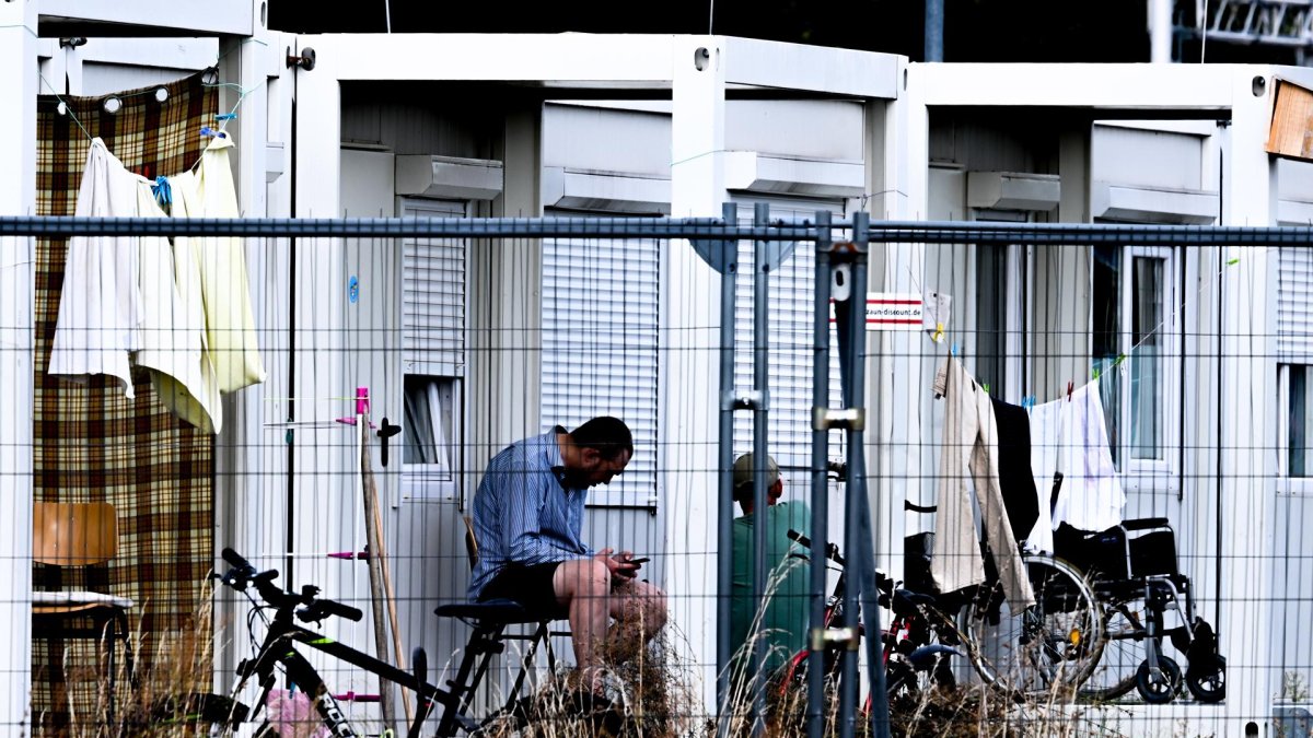 Un refugiado se sienta frente a contenedores usados como casas de acogida en el antiguo aeropuerto de Tegel.