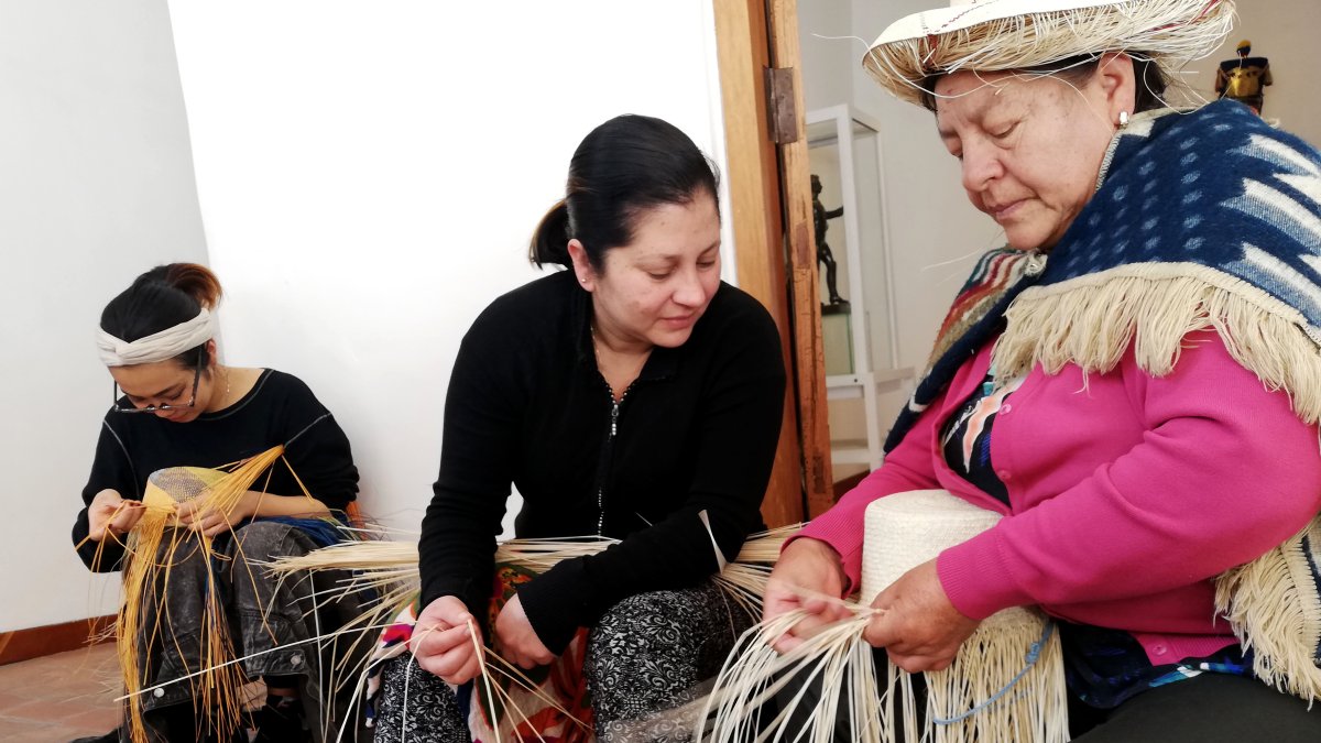 Labores. Blanca Guambaña enseña la forma de ir trenzando las hebras para darle forma al sombrero.