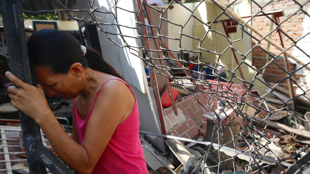 Mónica Grajales llora en la puerta de su vivienda destruida por un carro bomba, en el municipio de Jamundí.