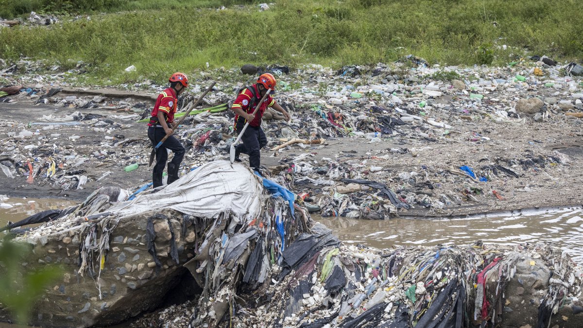 Bomberos trabajan para recuperar los cuerpos de víctimas que fueron arrastradas por el desbordamiento de un río, en el lecho del Río Las Vacas,