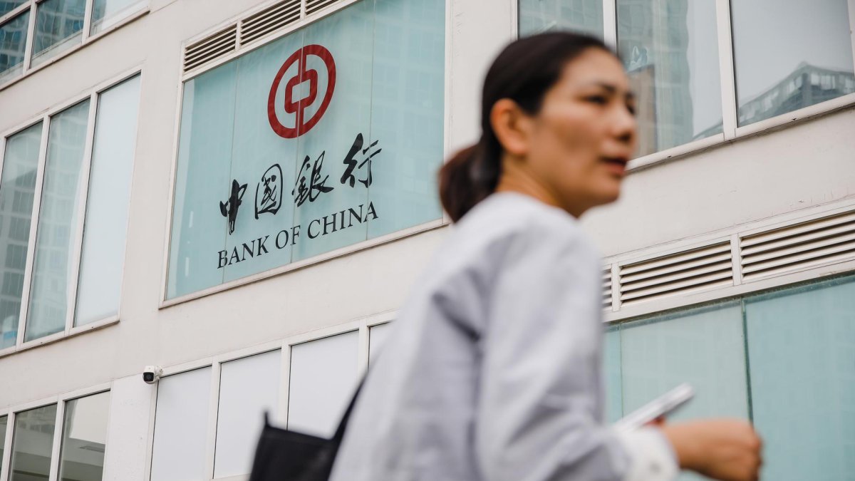 Una mujer camina este lunes frente a un banco en Pekín.