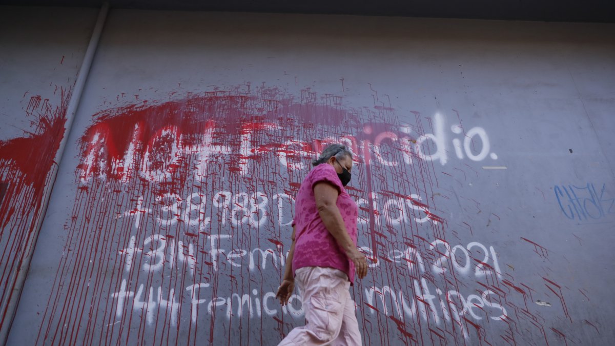 una mujer al caminar frente a un aviso pintado en una pared en contra del femicidio en Honduras, en una calle de Tegucigalpa.