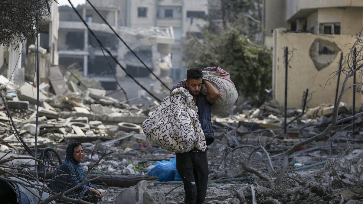 Una mujer palestina (L) sentada entre los escombros del barrio destruido de Al-Ramal tras un ataque aéreo israelí en la ciudad de Gaza, el 10 de octubre de 2023.