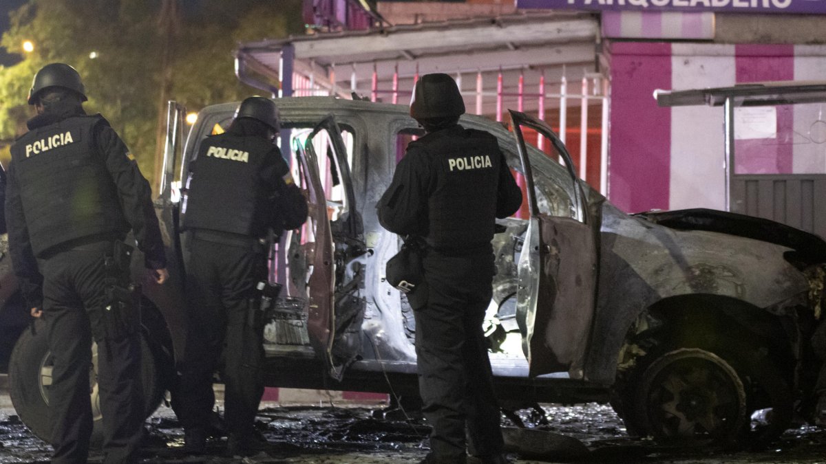 Fotografía de archivo fechada el 31 de agosto de 2023 que muestra a un grupo de policías junto a los restos de un carro bomba que explotó en los exteriores del edificio del Servicio Nacional de Atención Integral a Personas Privadas de Libertad (SNAI), en Quito (Ecuador).