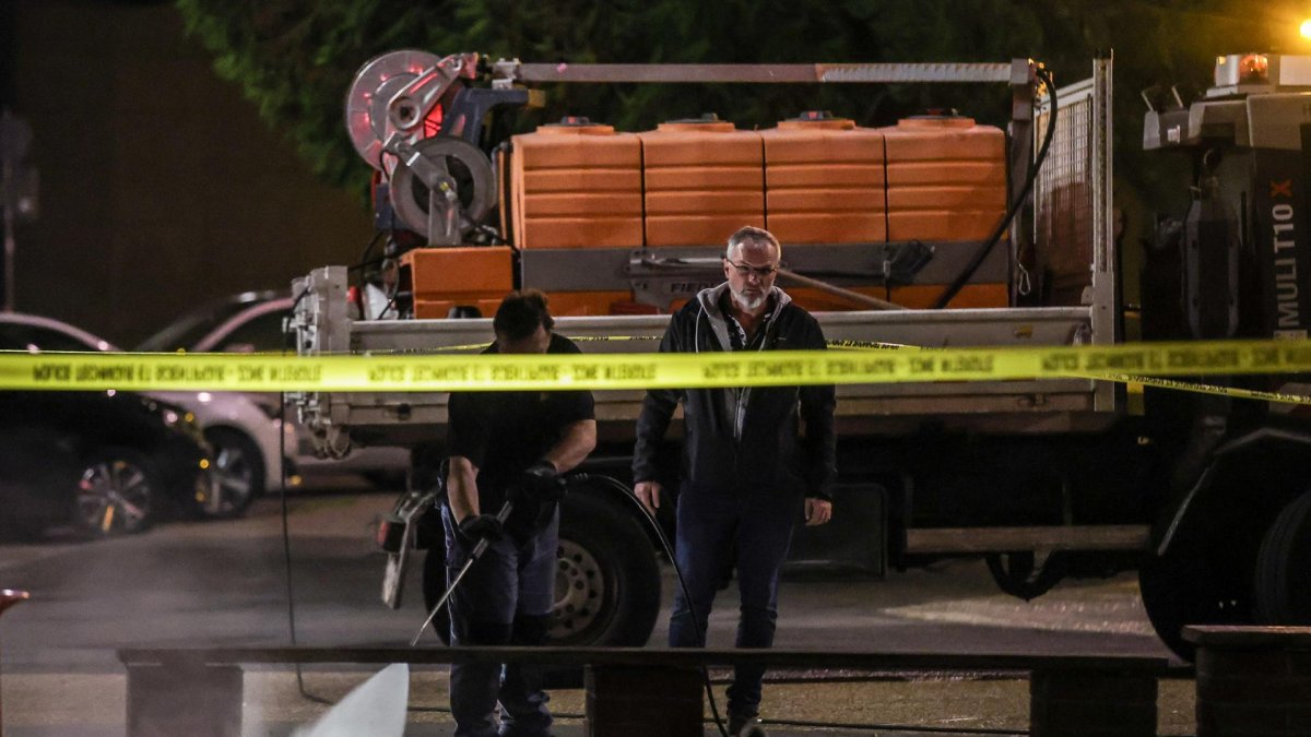 Policías limpian los exteriores del colegio donde se registró el ataque al profesor.