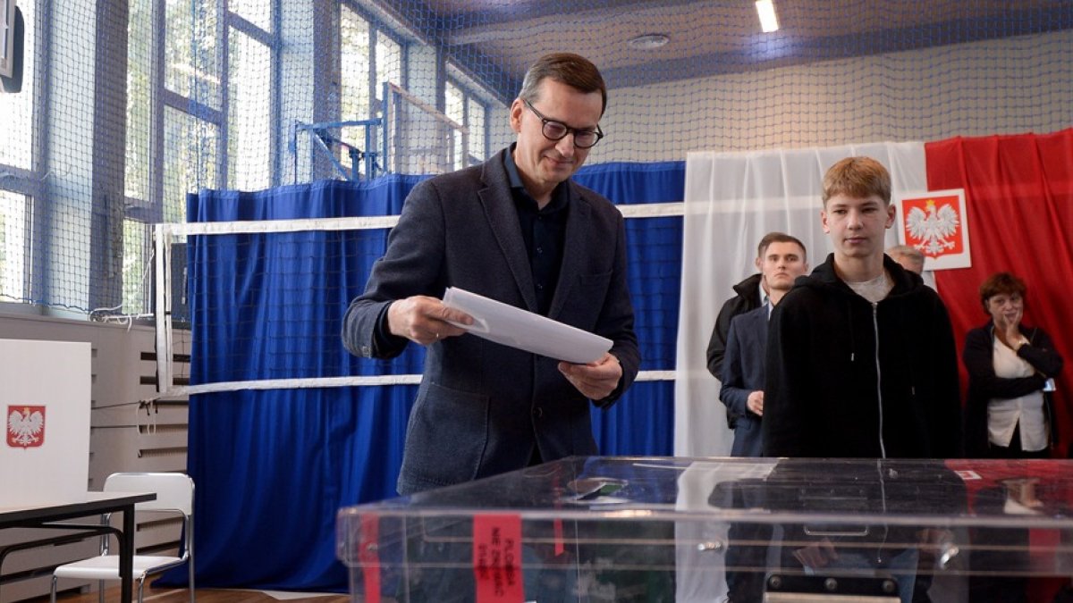 El primer Ministro polaco, Mateusz Morawiecki (c), deposita su voto en Varsovia