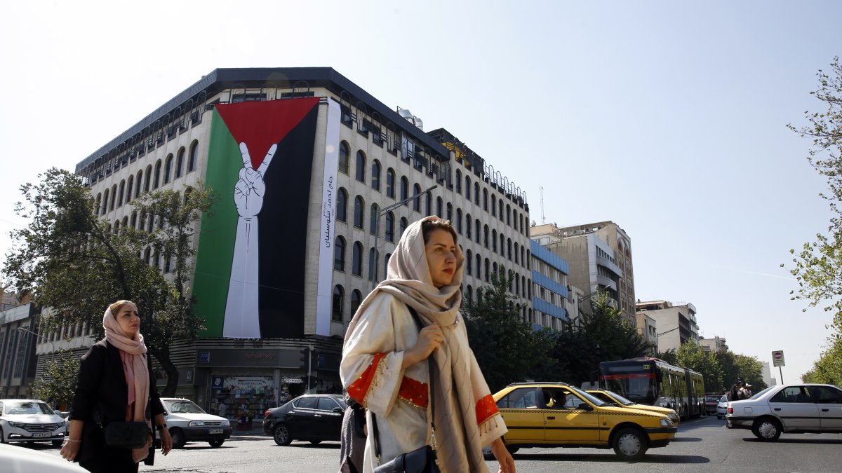 Teherán. Mujeres iraníes caminan junto a una enorme bandera palestina colgada en un edificio en esta capital.