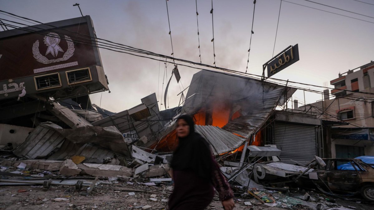 Una mujer palestina camina junto a una panadería destruida en el campo de refugiados de Al Nusairat, en el centro de la Franja de Gaza.