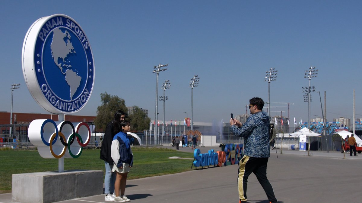 Varias personas se toman fotos afuera del Estadio Nacional. Es la primera vez que Chile acoge una cita de este tipo, pero deja dudas.