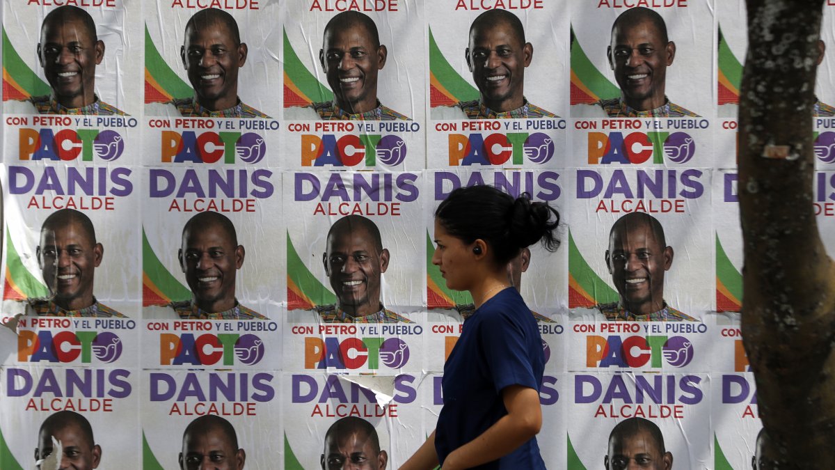 Votaciones. Una votante en Cali camina frente a un muro lleno de propaganda electoral. Este proceso se ha caracterizado, además de la violencia, por reunir candidatos llamativos.