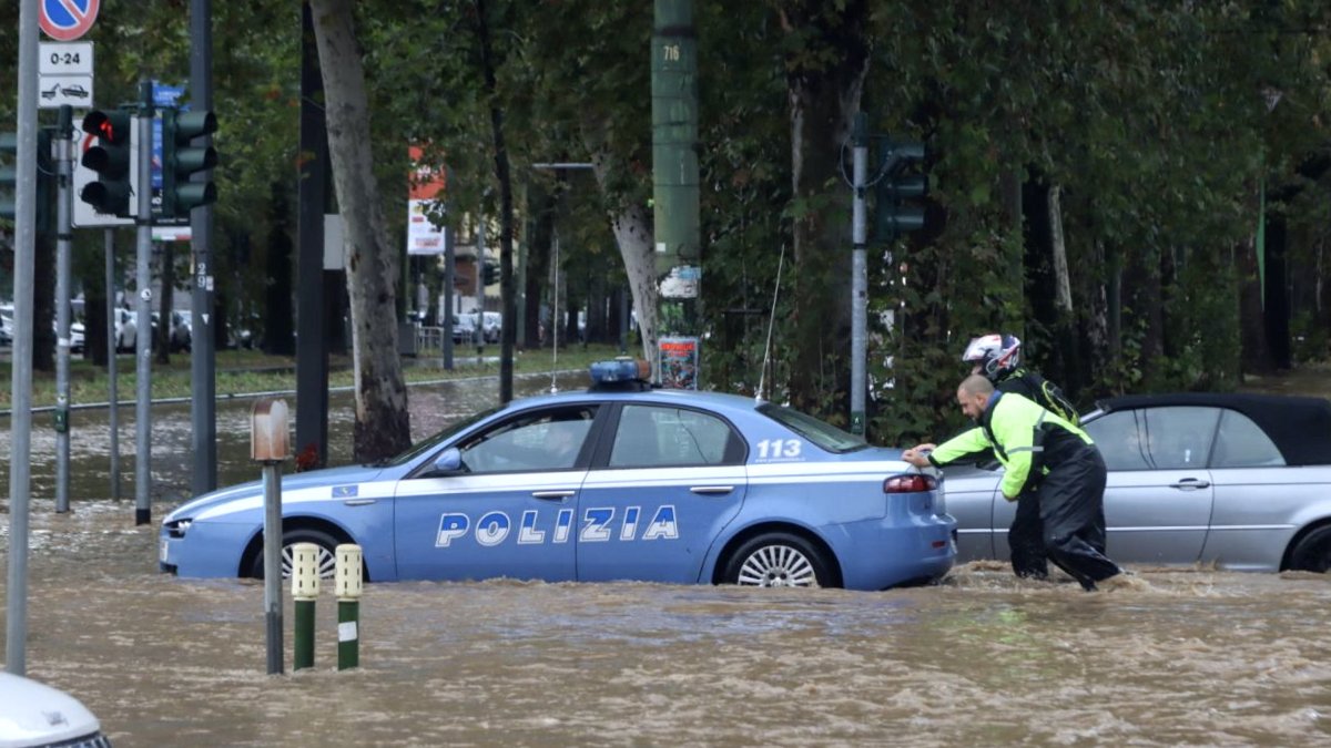 Milán. Un par de agentes empujan a un patrullero, afectado por el agua.