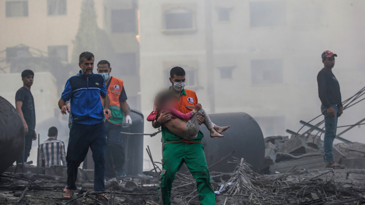 Gaza. Un palestino carga a una niña herida que ha sido recuperada de entre los escombros.