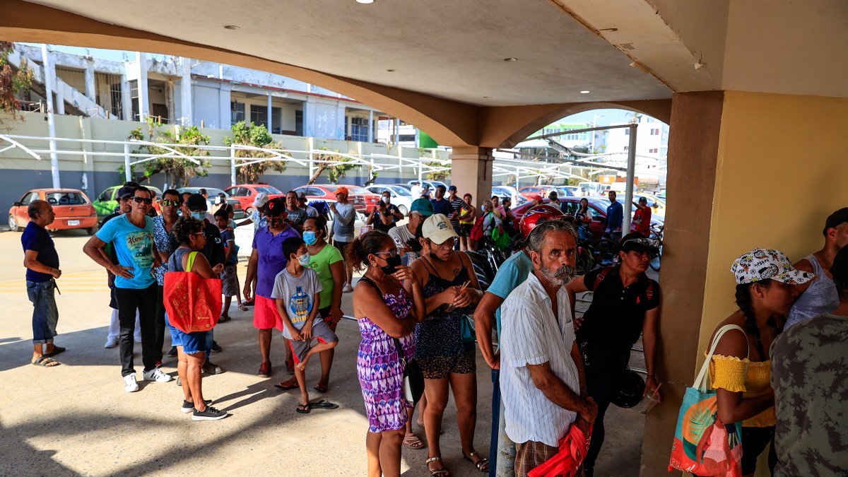 Personas hacen fila para adquirir productos en una tienda de autoservicio, tras el paso del huracán Otis en el balneario de Acapulco, en el estado de Guerrero (México).