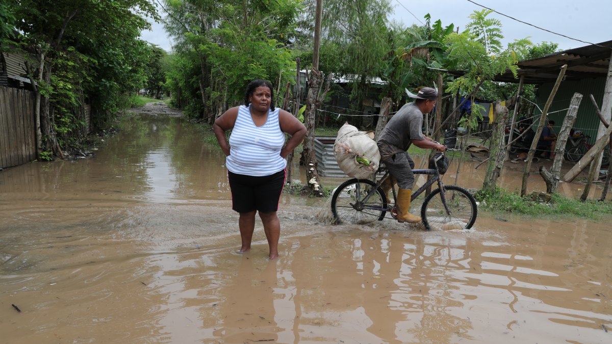 Residentes transitan una calle inundada hoy, en la Colonia Jehová Jireth del municipio de San Manuel, departamento de Corte (Honduras).