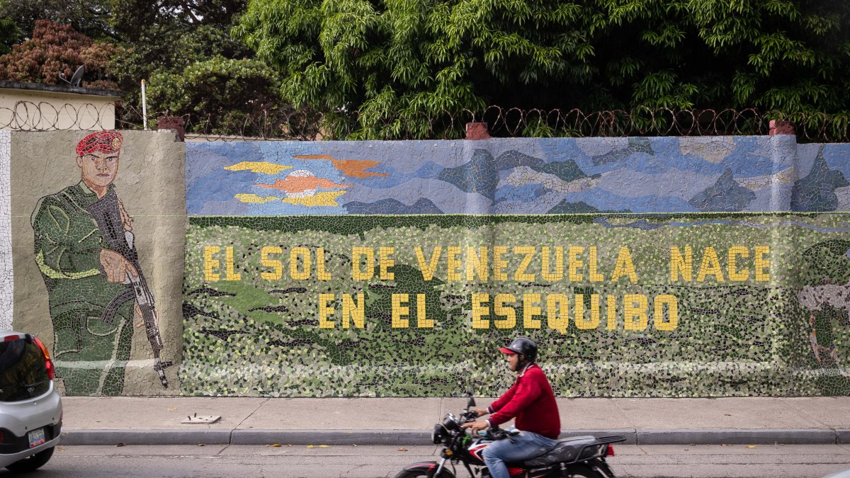 Un hombre conduce una moto frente a un mural que dice 
