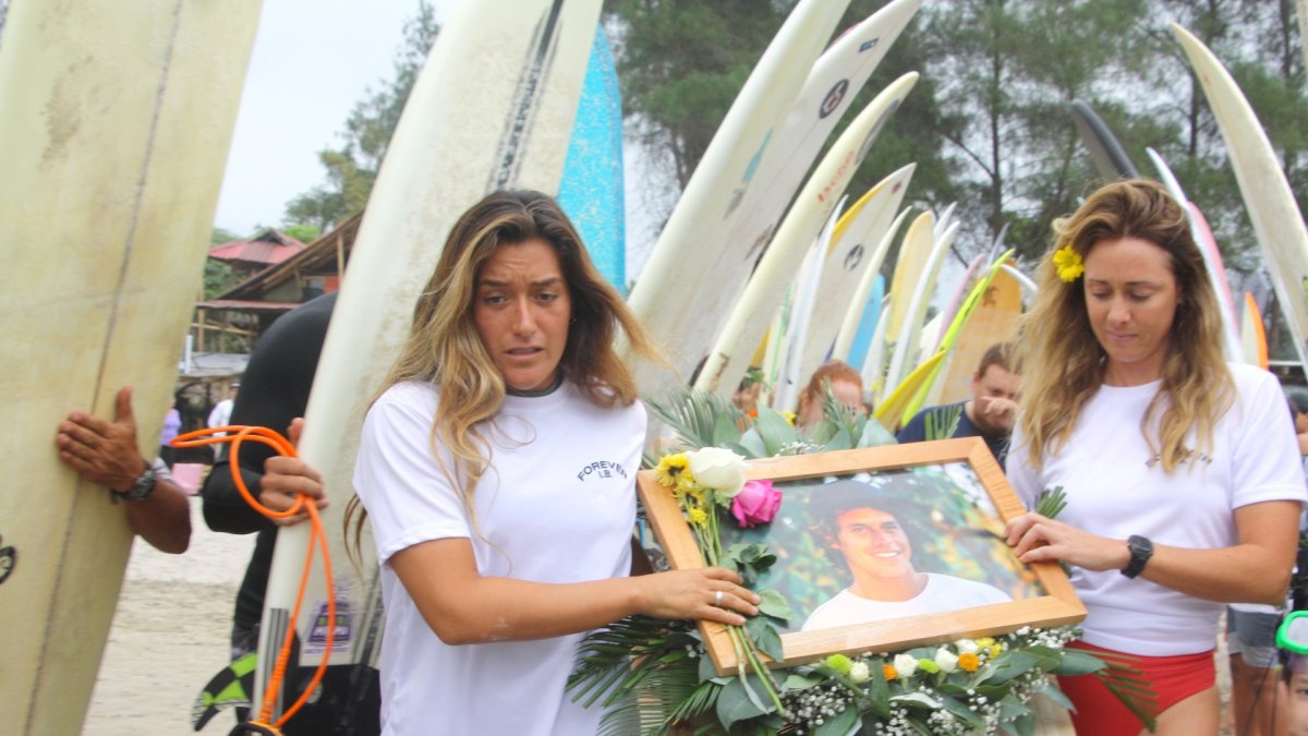 Mimi Barona, hermana de Israel, y la esposa del surfista llevan la ofrenda que se depositó en el mar.