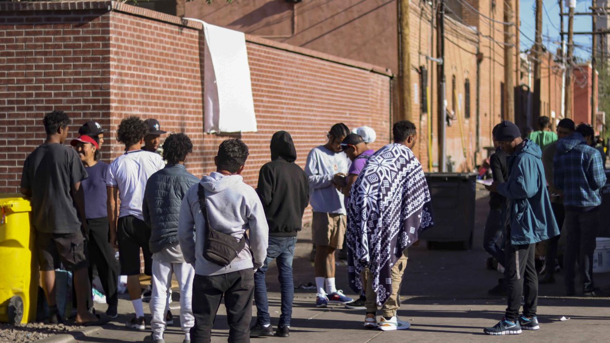 Decenas de inmigrantes esperan en un callejón en las afueras de la Iglesia de Sagrado Corazón de Jesús, en la ciudad de El Paso, Texas (EE.UU.)