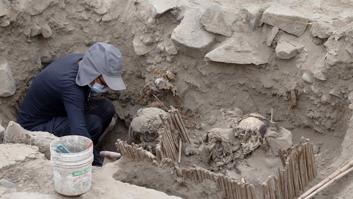 Aarqueólogos mientras trabajan con momias halladas en una pirámide prehispánica, en Lima (Perú).