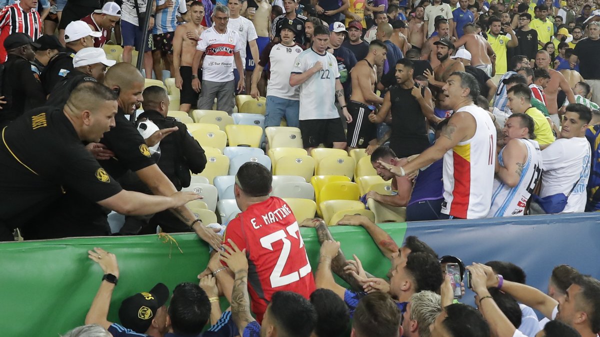 Emiliano Martínez (c) portero de Argentina intenta controlar disturbios entre hinchas de Brasil y de Argentina.