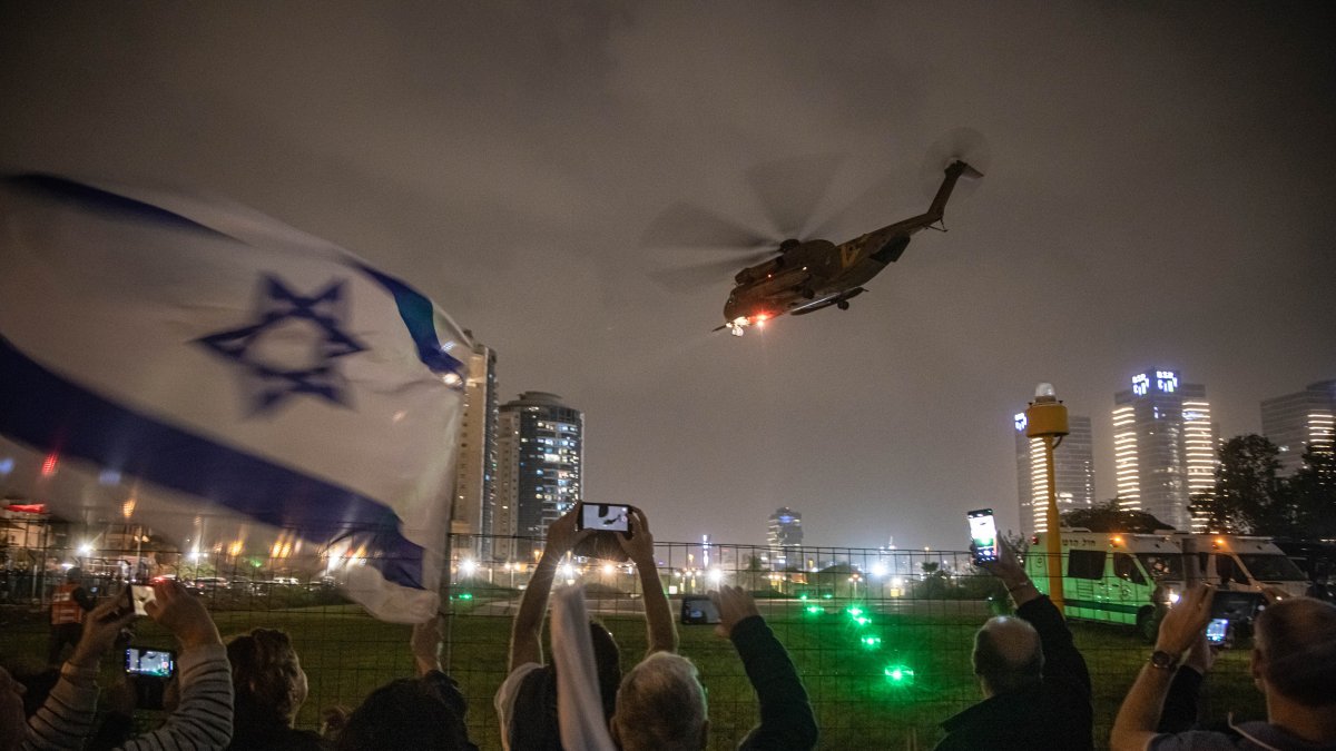 La gente anima mientras un helicóptero del ejército israelí transporta a rehenes recientemente liberados en el Centro Médico Infantil Schneider en Petah Tikva, en Tel Aviv, el 26 de noviembre de 2023.