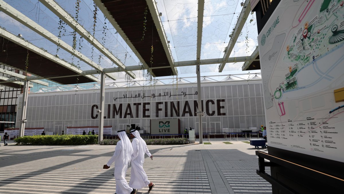 Dubái. Varias personas transitan junto al logotipo de la COP28.