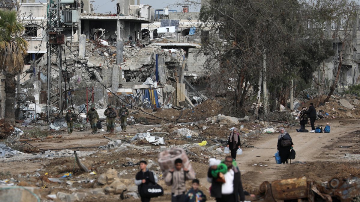Palestinos caminan después de cruzar desde el norte de la Franja de Gaza al sur de la Franja de Gaza mientras los soldados israelíes avanzan por la carretera Salah Al Din en el centro de la Franja de Gaza.
