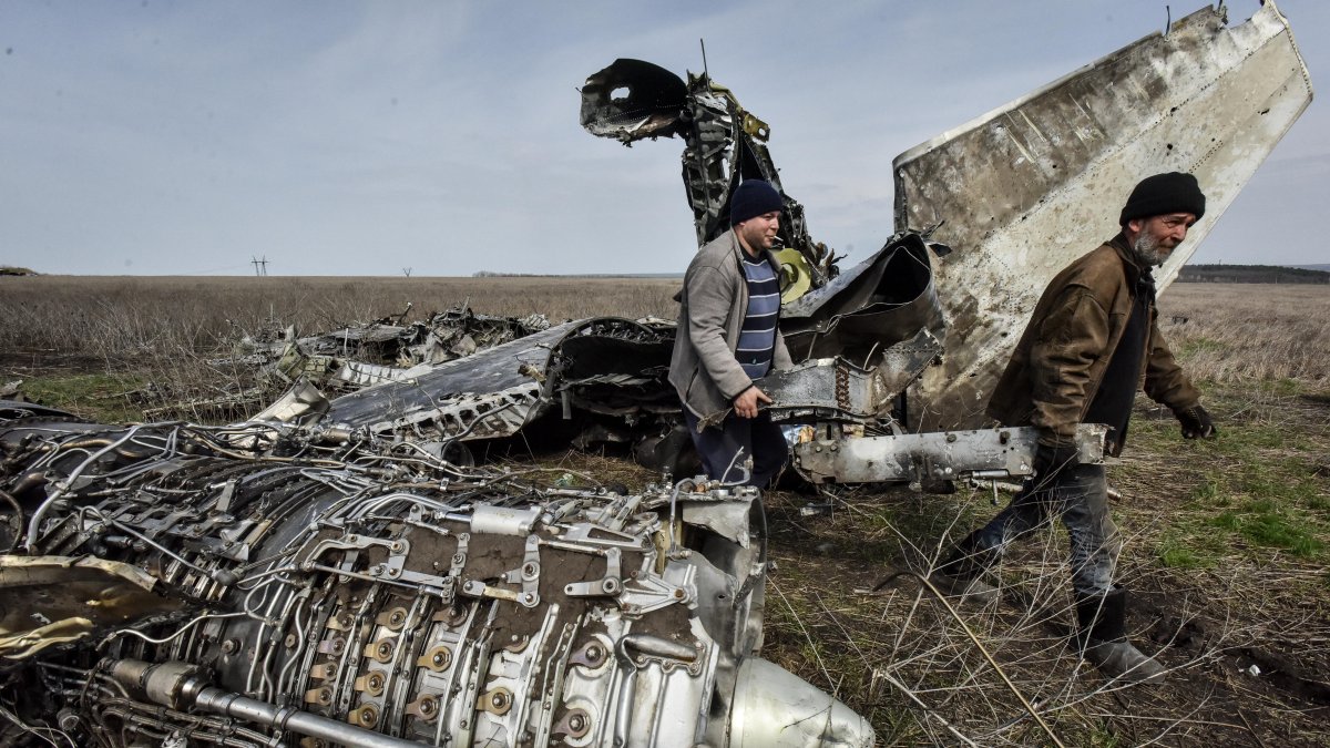 Residentes locales recogen chatarra de un avión de combate estrellado en la región de Kharkiv, Ucrania.