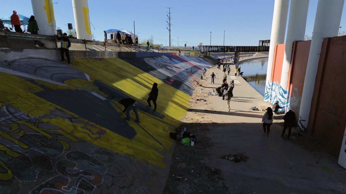 Activistas pintan un mural para denunciar la violencia de género y el maltrato a los migrantes, junto al río Bravo en Ciudad Juárez, estado de Chihuahua (México).