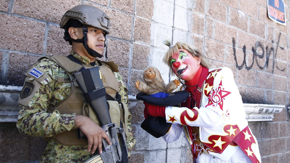Un payaso bromea con un soldado durante un desfile con motivo del día del payaso salvadoreño hoy, en San Salvador (El Salvador).