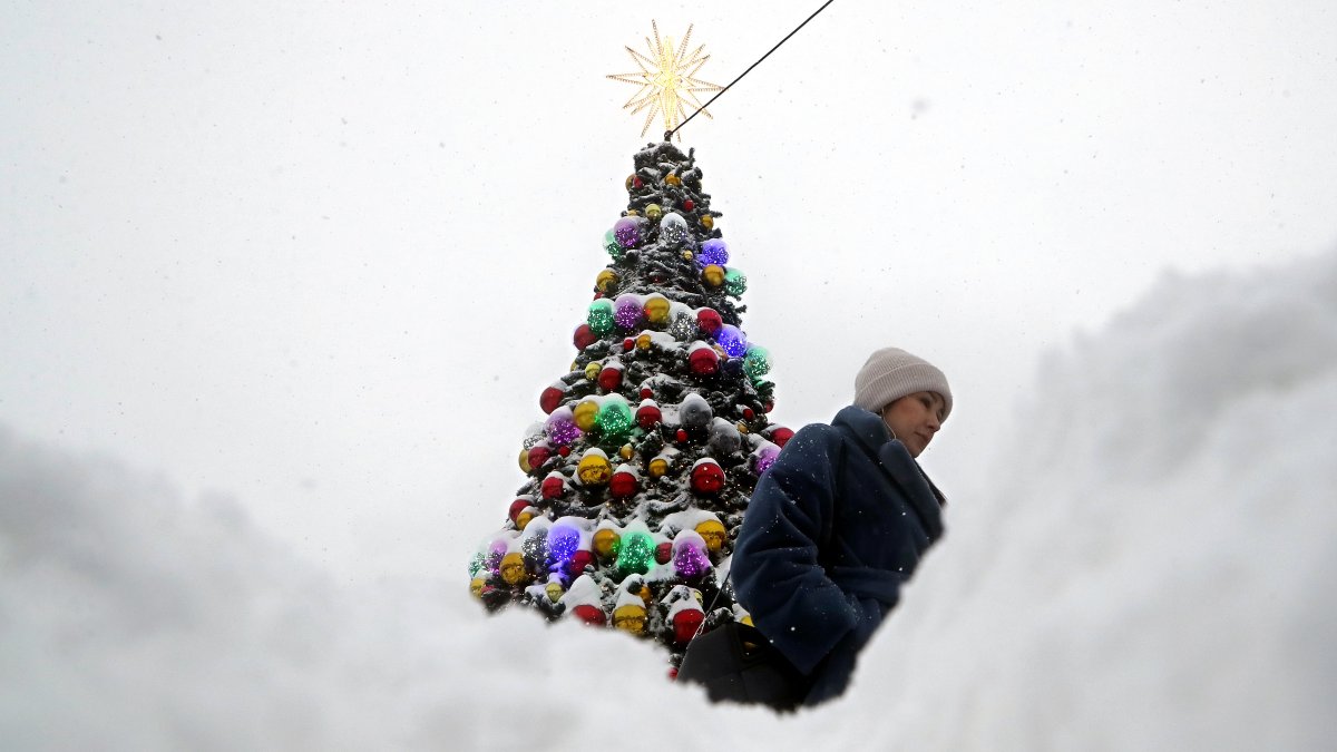 Una mujer camina junto a un árbol de Navidad cubierto de nieve tras una fuerte nevada en Moscú, Rusia, el 15 de diciembre de 2023.