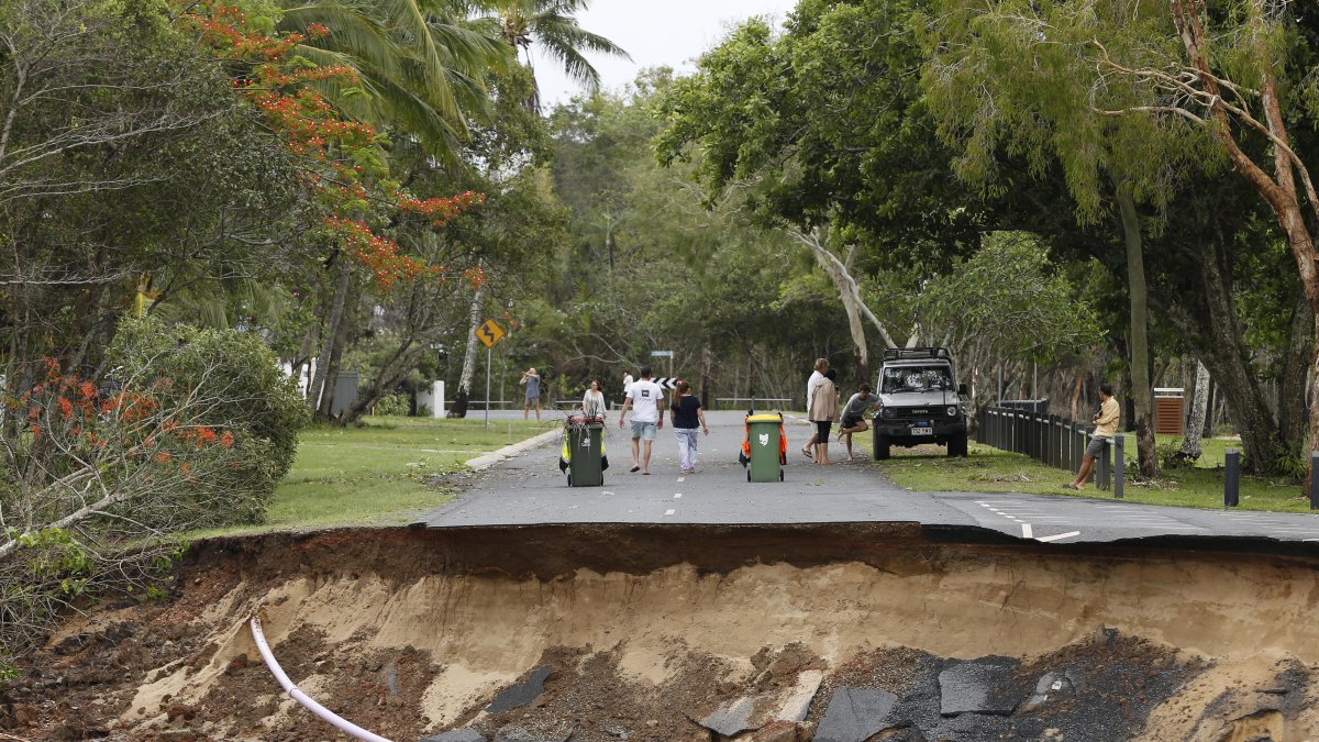 Un grupo de personas observan la vía interrumpida, a causa de las lluvias torrenciales que caen desde hace cinco días.