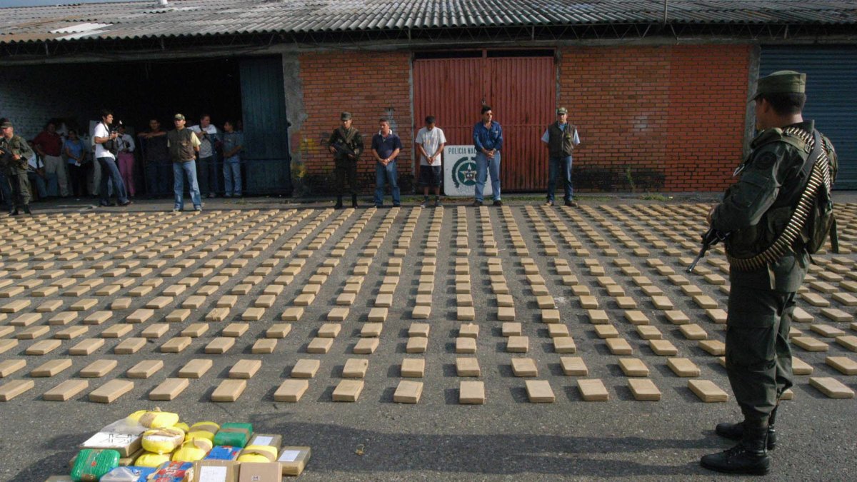 Un agente de la Policía Metropolitana de Cali custodia un cargamento de cocaína incautado en un contenedor de fruta, en la zona de carga del aereropuerto Rodrigo Bonilla Aragón, en Cali (Colombia).