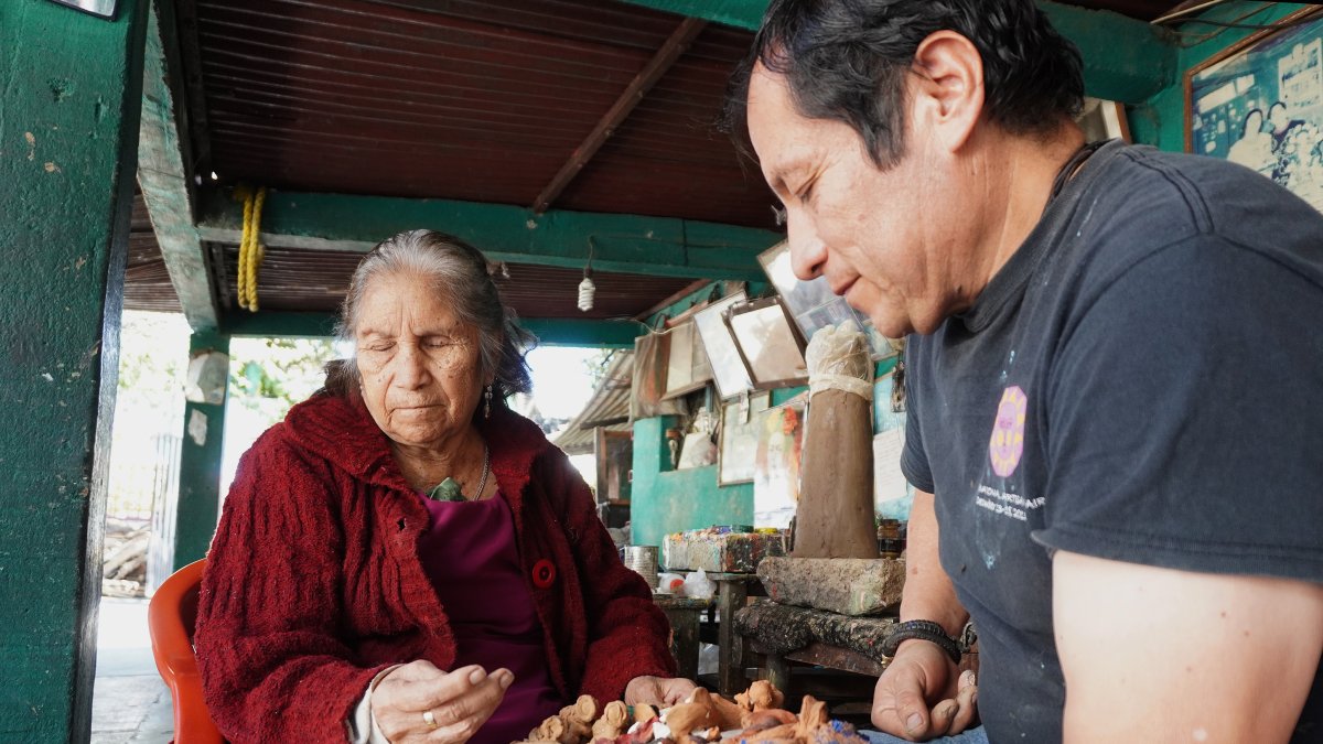 Los artesanos Josefina Aguilar (i), y su hijo Demetrio, elaboran nacimientos miniatura de barro, el 23 de diciembre de 2023, en la ciudad de Oaxaca (México).