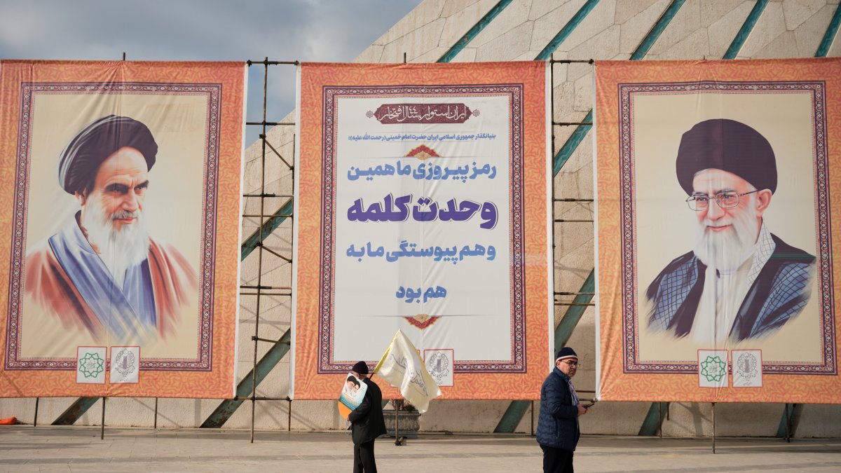 Dos hombres pasan frente a los retratos del líder supremo de Irán, Ali Jameneí, y ayatolá Ruholá Jomeiní durante la conmemoración del 44º aniversario del triunfo de la Revolución Islámica en Teherán.