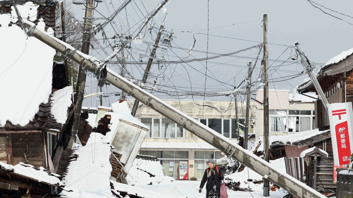 Suzu. Unas personas caminan bajo líneas eléctricas caídas en esta ciudad japonesa, afectada por el terremoto del 1 de enero de 2024.