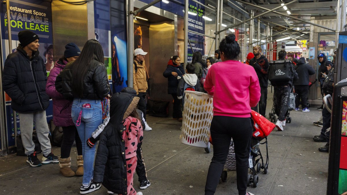 Personas con bolsas de pertenencias y cochecitos abandonan el hotel Row NYC.