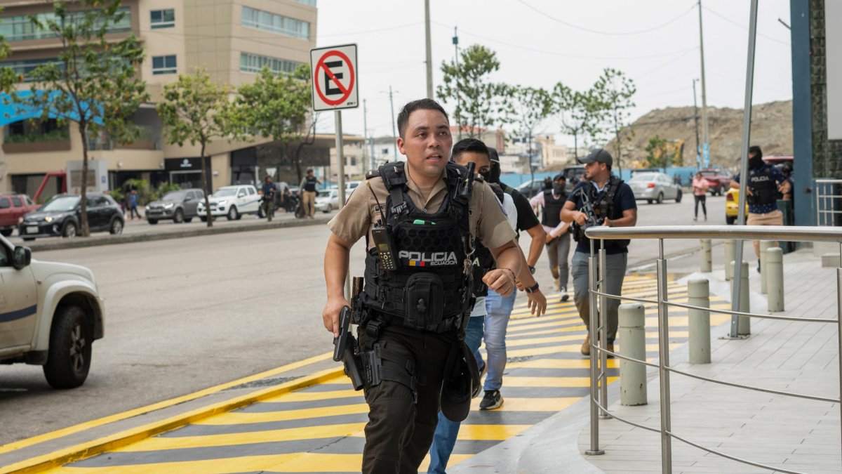 Policías persiguen hoy a un presunto delincuente a pocas cuadras de la sede del canal de televisión TC, donde encapuchados armados ingresaron y sometieron a su personal durante una transmisión en vivo, en Guayaquil