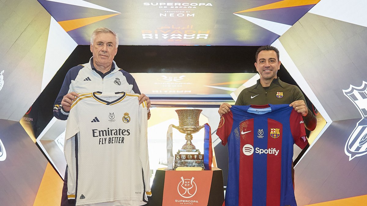 Los entrenadores Carlo Ancelotti (i) y Xavi (d) junto al trofeo de la Supercopa de España.