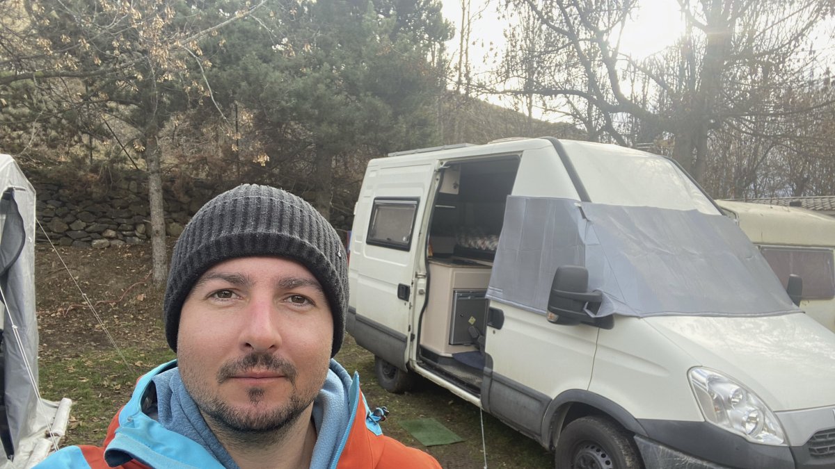 Óscar Fernández Quiles se toma una foto junto a la furgoneta en la que vive. Cataluña enfila el 2024 con un mercado de la vivienda