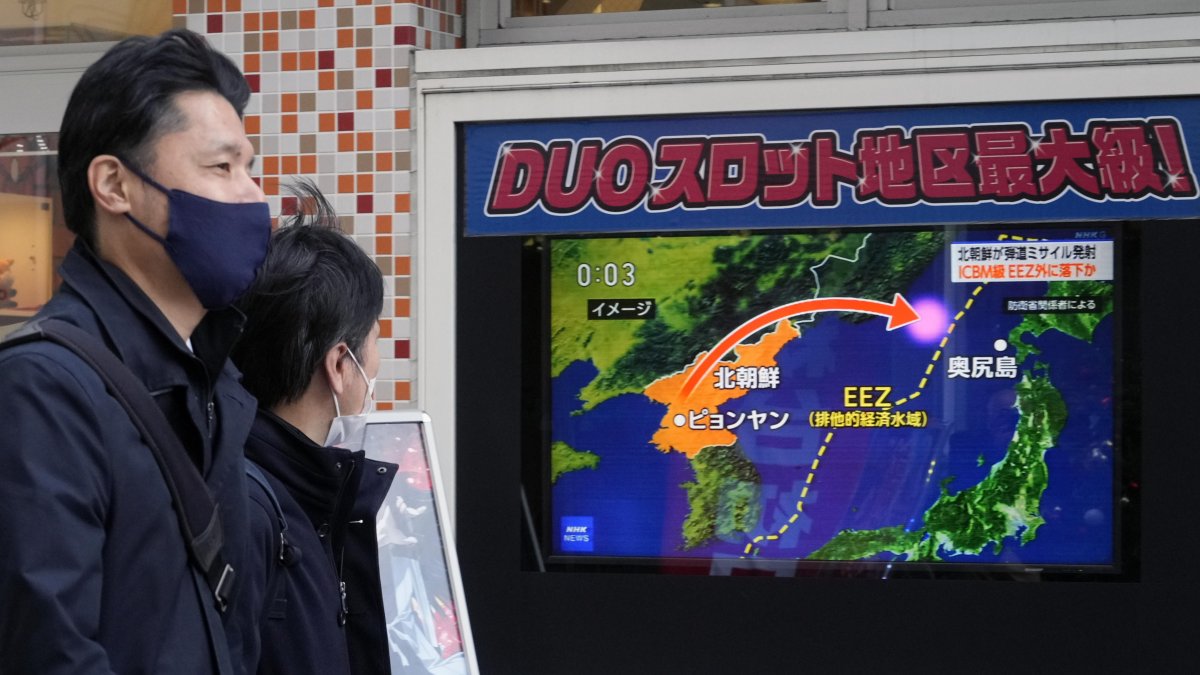 Imagen de unos viandantes observando en un monitor un lanzamiento de un misil balístico norcoreano.