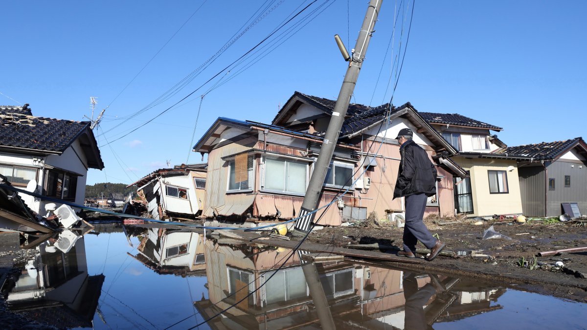 Una persona transita por una zona inundada, escenario del fuerte terremoto que afectó a Japón el 1 de enero de 2024, en la prefectura de Ishikawa.