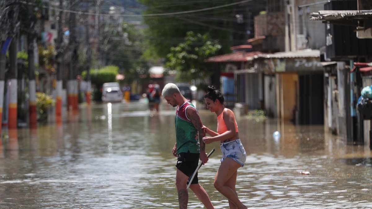 Habitantes transitan por una calle inundada tras las lluvias de los últimos días, en el municipio de Duque de Caxias, en la región Baixada Fluminense, área metropolitana de Río de Janeiro (Brasil).