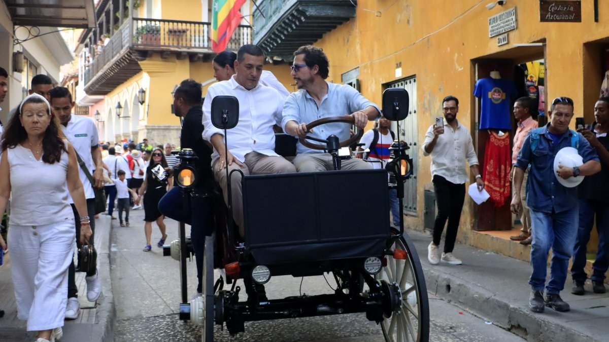 El comediante Alejandro Riaño (d) y el alcalde de Cartagena, Dumek Turbay (i), prueban el prototipo de coche eléctrico