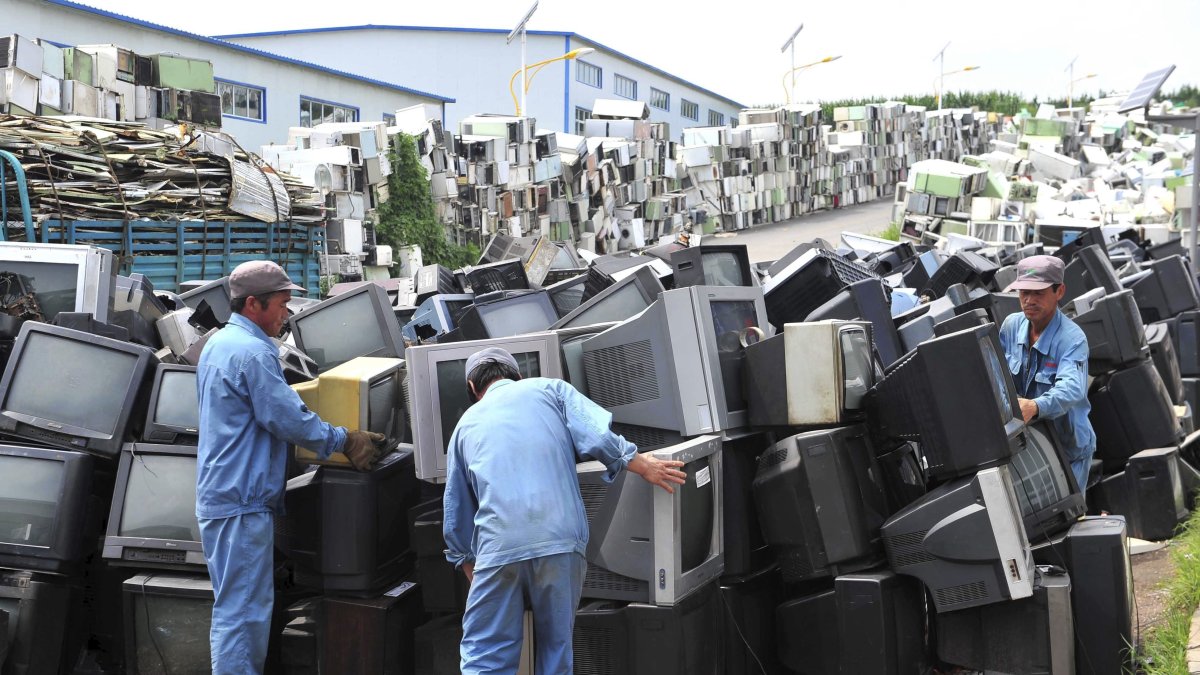 Trabajadores desarman electrodomésticos y artículos electrónicos en un centro de reciclaje en Tieling City, al noreste de China, en una imagen de archivo.