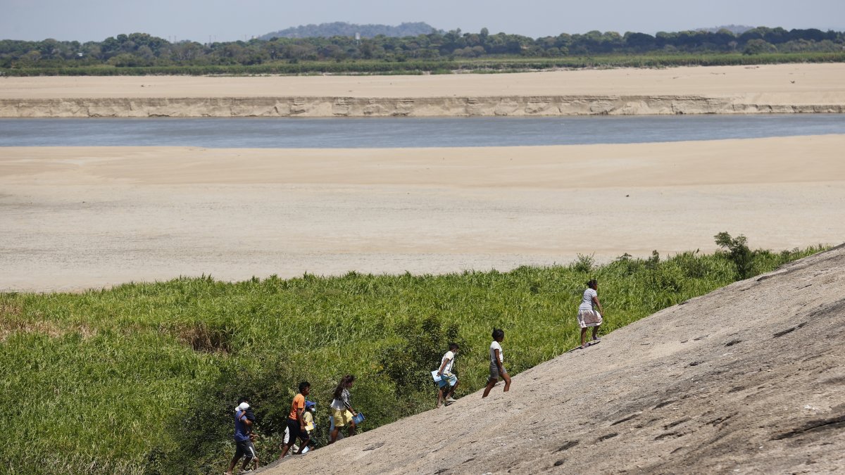 Varios desplazados caminan cerca de un río de Colombia.