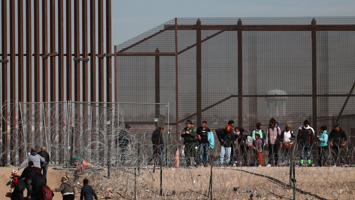 Ciudad Juárez. Migrantes se abren paso a un costado de la cerca de alambres en la frontera que divide a México de los EE. UU.